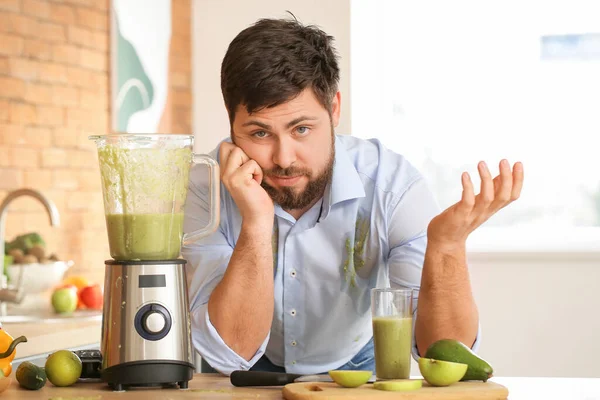 Clumsy man with spilled smoothie in kitchen