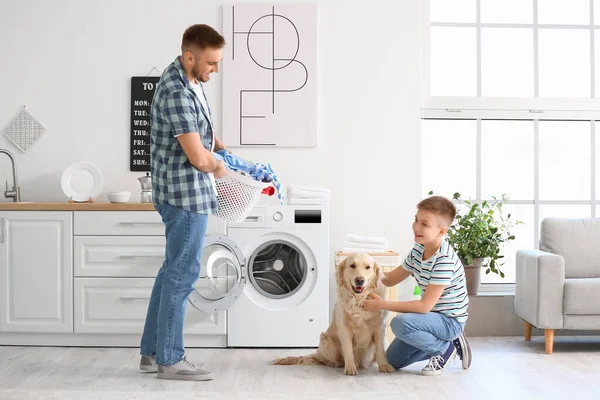 stock image Man and his little son with cute dog doing laundry at home