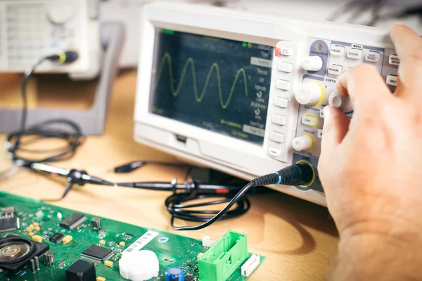 Inženýr testuje elektronické součástky s osciloskop v servisním středisku — Stock fotografie