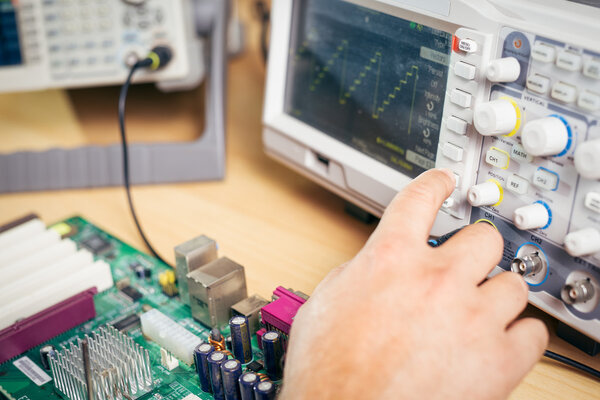 Engineer tests electronic components with oscilloscope in the service center