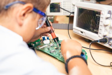 Bir elektronik proje üzerinde çalışan bir genç çocuk
