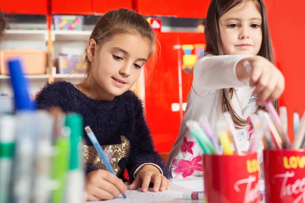 Zwei kleine Mädchen zeichnen auf Papier am Tisch — Stockfoto