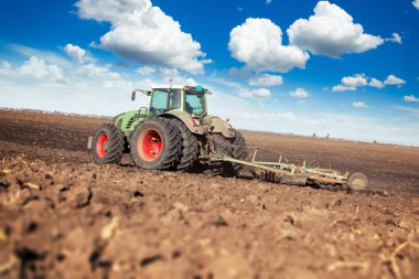 Traktördeki çiftçi tohum ekiciyle toprağı hazırlıyor.
