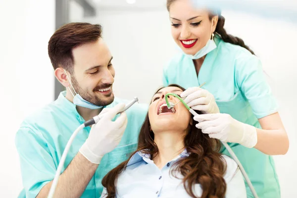 Dentista en el trabajo. Paciente joven visitando consultorio del dentista — Foto de Stock