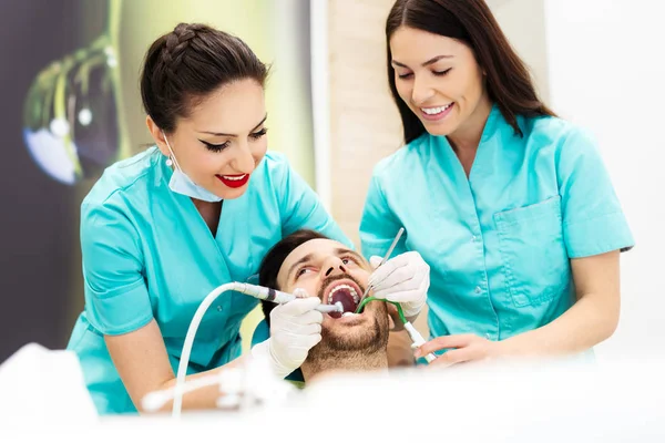 Dentista feminina tratando o paciente masculino na cadeira do dentista, usando broca dentária . — Fotografia de Stock