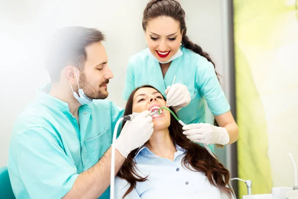 Um dentista com assistente trabalhando em um paciente — Fotografia de Stock
