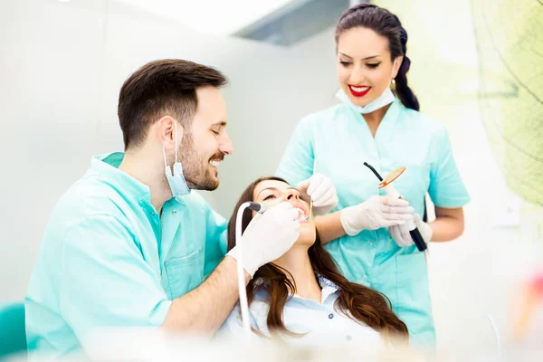 Un dentista con asistente trabajando en un paciente — Foto de Stock