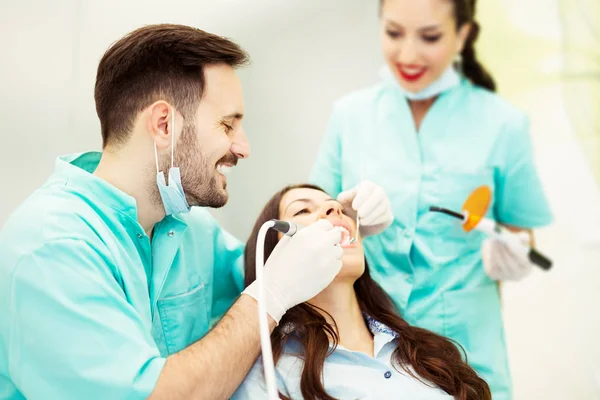 Un dentista con asistente trabajando en un paciente — Foto de Stock