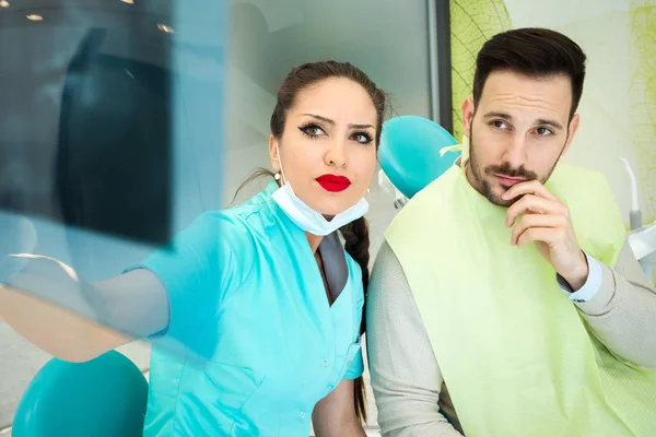 Dentista femenina examinando imagen de rayos X de dientes en clínica dental — Foto de Stock