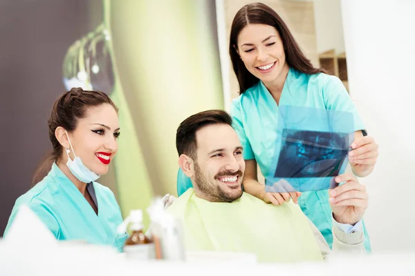 El dentista muestra una imagen de rayos X del paciente —  Fotos de Stock