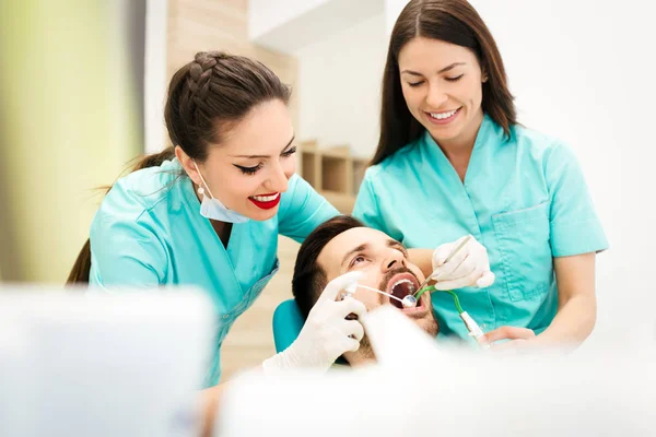 Female dentist examining a male patient at clinic — Stock Photo, Image