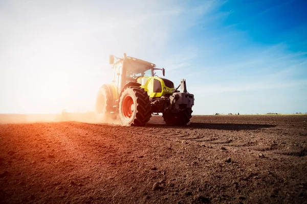 Traktor som arbetar på jordbruksmark på sunset — Stockfoto