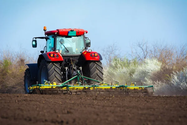 Agricultor en tractor preparando tierra con cultivador de semillero —  Fotos de Stock