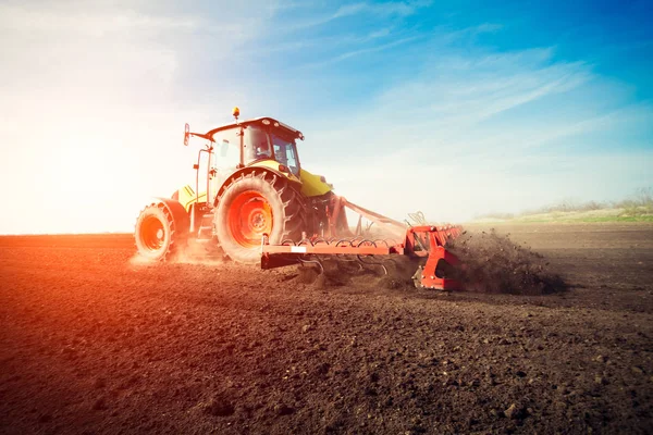 Trator trabalhando em terras agrícolas ao pôr do sol — Fotografia de Stock