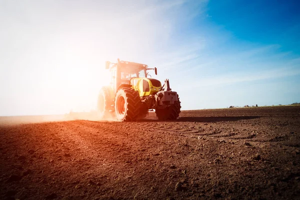 Trattore che lavora su terreni agricoli al tramonto — Foto Stock