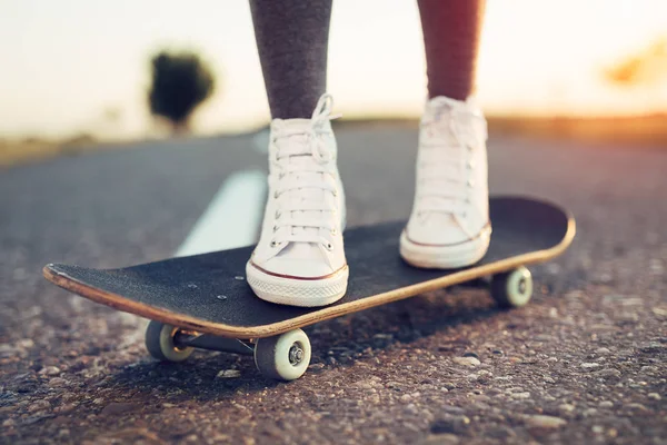 Skateboarden benen van de vrouw bij zonsopgang straat — Stockfoto