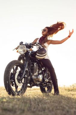 Motosikletli kız. Çok güzel, gün batımında motosiklette poz veriyor.