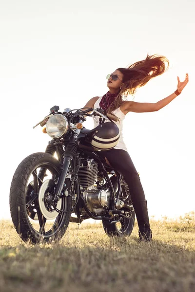 Rapariga numa mota. Ela é linda, posando em uma motocicleta ao pôr do sol — Fotografia de Stock