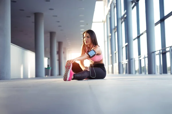 De uitrekkende benen atletische vrouw vóór uitvoeren — Stockfoto