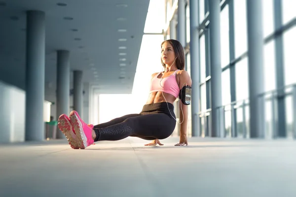 Aantrekkelijke sport vrouw doet push ups binnenshuis — Stockfoto