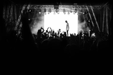 Siluetleri insanların parlak ışık sahne önünde bir konserde. Siyah ve beyaz