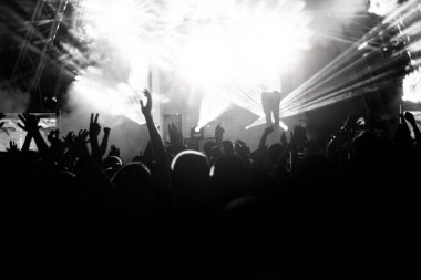 Siluetleri insanların parlak ışık sahne önünde bir konserde. Siyah ve beyaz