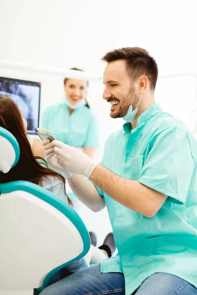 Dentista verificando e selecionando a cor dos dentes da jovem — Fotografia de Stock