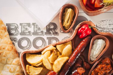 Bira ve snack ayarlayın. Çeşitli bira, ızgara sosis, patates kızartması, ahşap arka plan üzerinde tuzlu