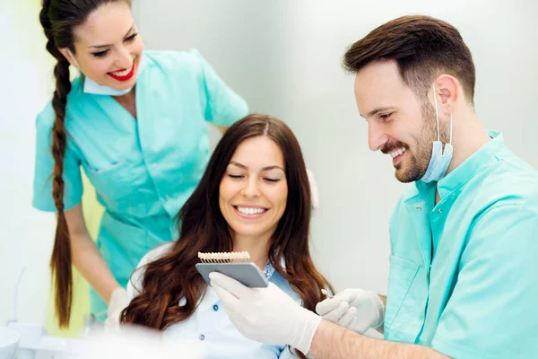 Dentista verificando e selecionando a cor dos dentes da jovem — Fotografia de Stock