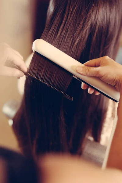 Cabeleireiro está alisando o cabelo — Fotografia de Stock
