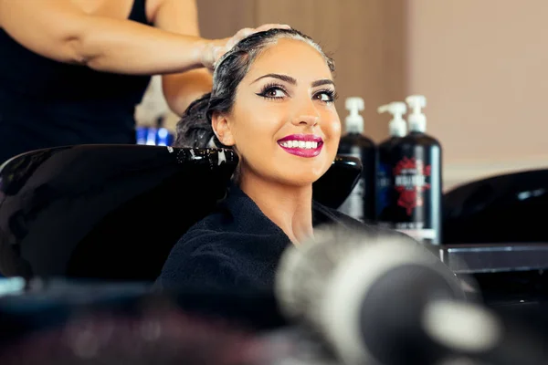 Bella giovane donna con parrucchiere che lava la testa a salone di capelli — Foto Stock