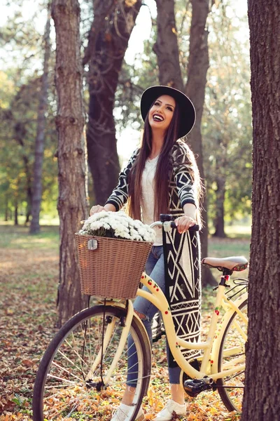 美丽的女人推着一辆自行车用一束它室外 — 图库照片