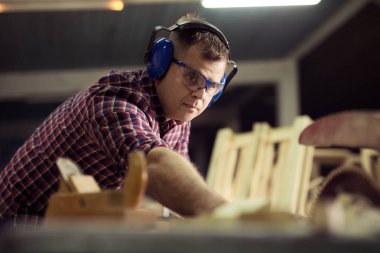 Marangoz marangozluk atölyesinde işini yapıyor.