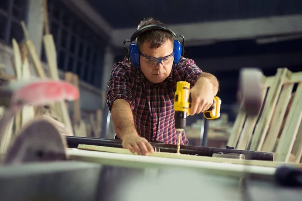 Timmerman met elektrische boor boren hout plank op workshop — Stockfoto