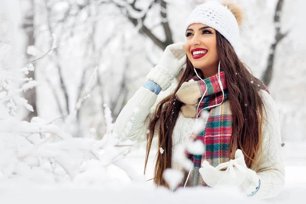 Woman listening music with her mobile phone in first snow