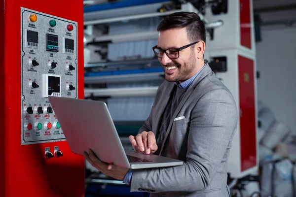 Engineer in the factory using laptop computer for maintenance.