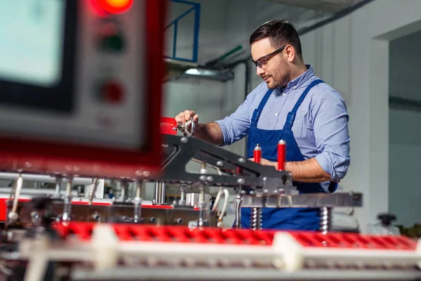 Factory worker maintaining plastic bag machine in the industry.