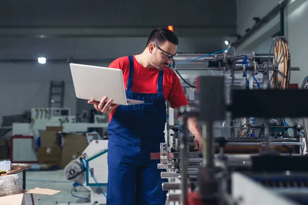 Engineer in the factory using laptop computer for maintenance.