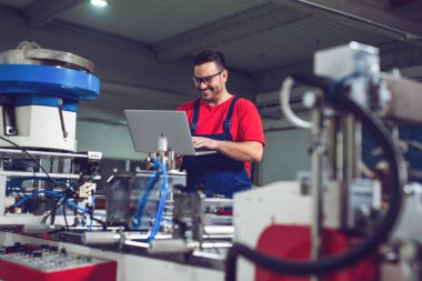 Endüstriyel imalat fabrikasında dizüstü bilgisayarı olan bir endüstri mühendisi.