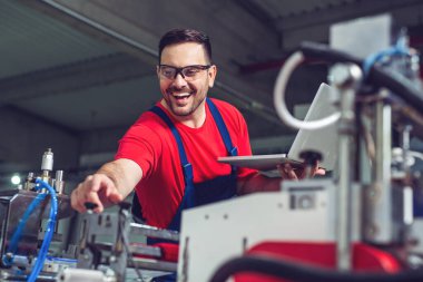 Endüstriyel imalat fabrikasında dizüstü bilgisayarı olan bir endüstri mühendisi.