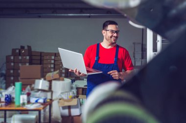 Endüstriyel imalat fabrikasında dizüstü bilgisayarı olan bir endüstri mühendisi.