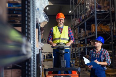 Forklift kontrol listesindeki lojistik deposunda çalışanlar.