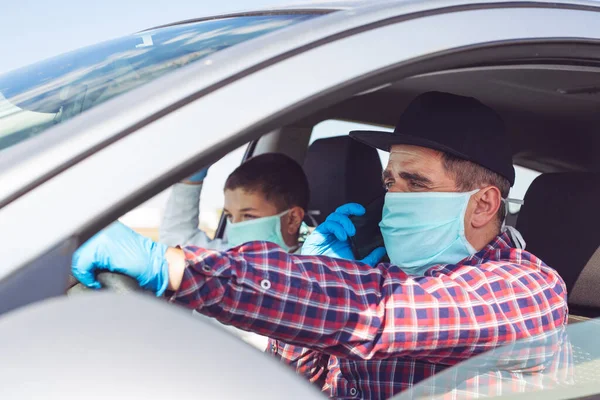 Man with protective mask and gloves driving a car. World pandemic. Stay safe.