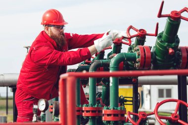 Petrol işçisi petrol platformunda vanayı çeviriyor.