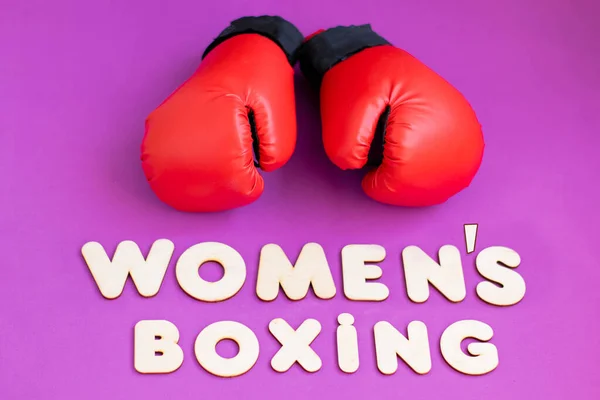 Red boxing gloves on a pink background and the inscription from the wooden letters \