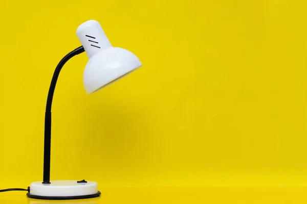 White table lamp on a yellow background. Free space for text.