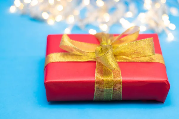 Box with a gift. Red box with a gold ribbon on a blue background. Gift for the new year, christmas.