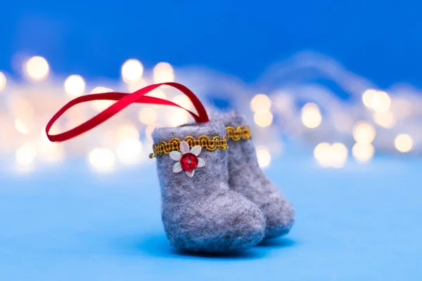 Decorative felt boots on a blue background with bokeh. Christmas mood, blurred background. Christmas tree decoration.