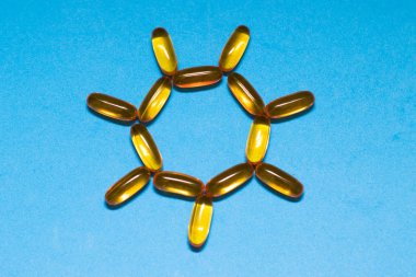 Güneş şeklinde balık yağlı kapsüller. Konsept, güneşin D vitamini emilimine D vitamini, Omega-3 vitamini kullanımına etkisi..