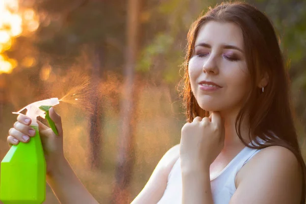 Mujer joven rociando agua sobre sí misma de una botella de spray, primer plano . — Foto de Stock